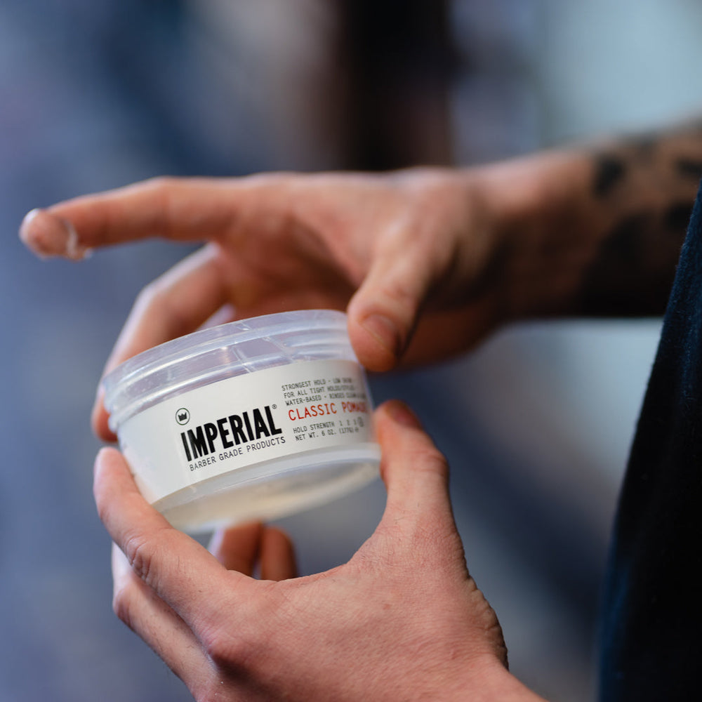 Hands opening a jar of Imperial pomade
